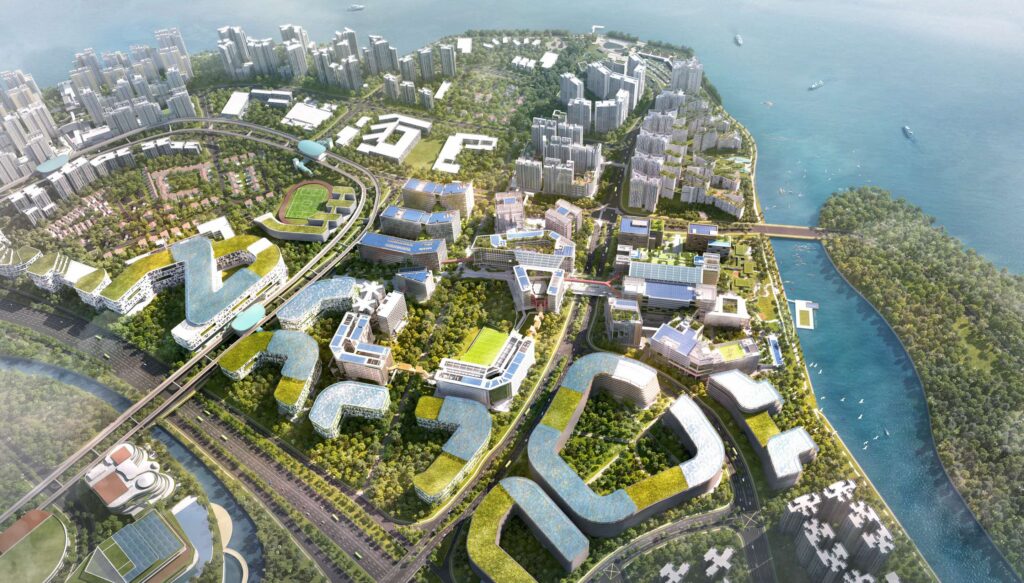 Aerial view of a modern cityscape next to a large body of water, featuring uniquely shaped, sustainable buildings with green rooftops and solar panels. The landscape includes several clusters of tall residential or office towers, sports fields, extensive greenery, a river, and a bridge connecting to a forested island. Boats are visible in the water.